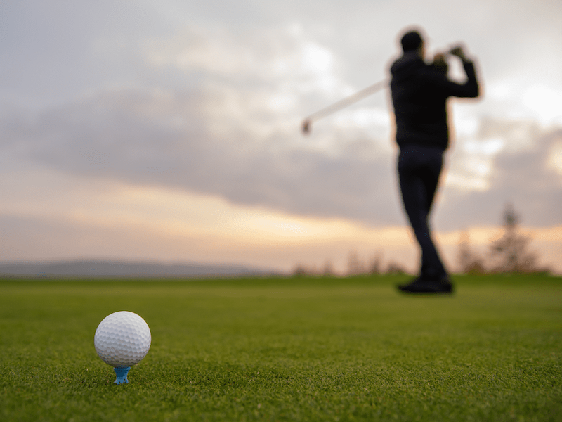 A golfer practicing their swing before hitting the ball off the tee.